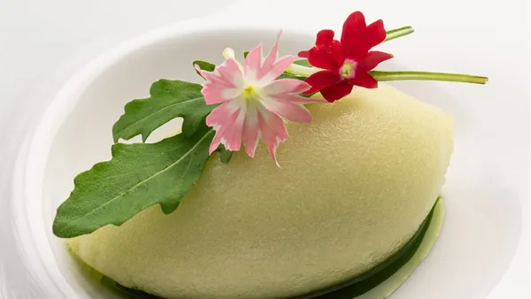 Sorbet de maçã do Picchi em formato de quenelle, verde-claro, sobre um fio de molho verde, com folha de rúcula e flores rosa e vermelha