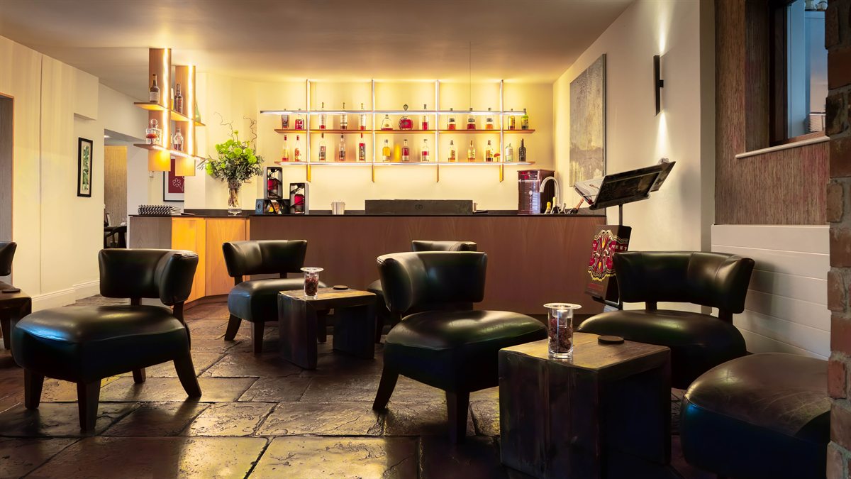 Bar do Restaurant Sat Bains, com poltronas de couro e prateleiras iluminadas