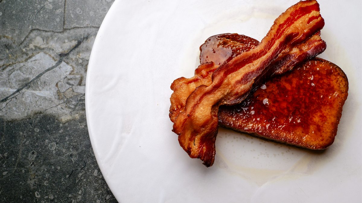 Rabanada de brioche com bacon crocante, servida num prato branco